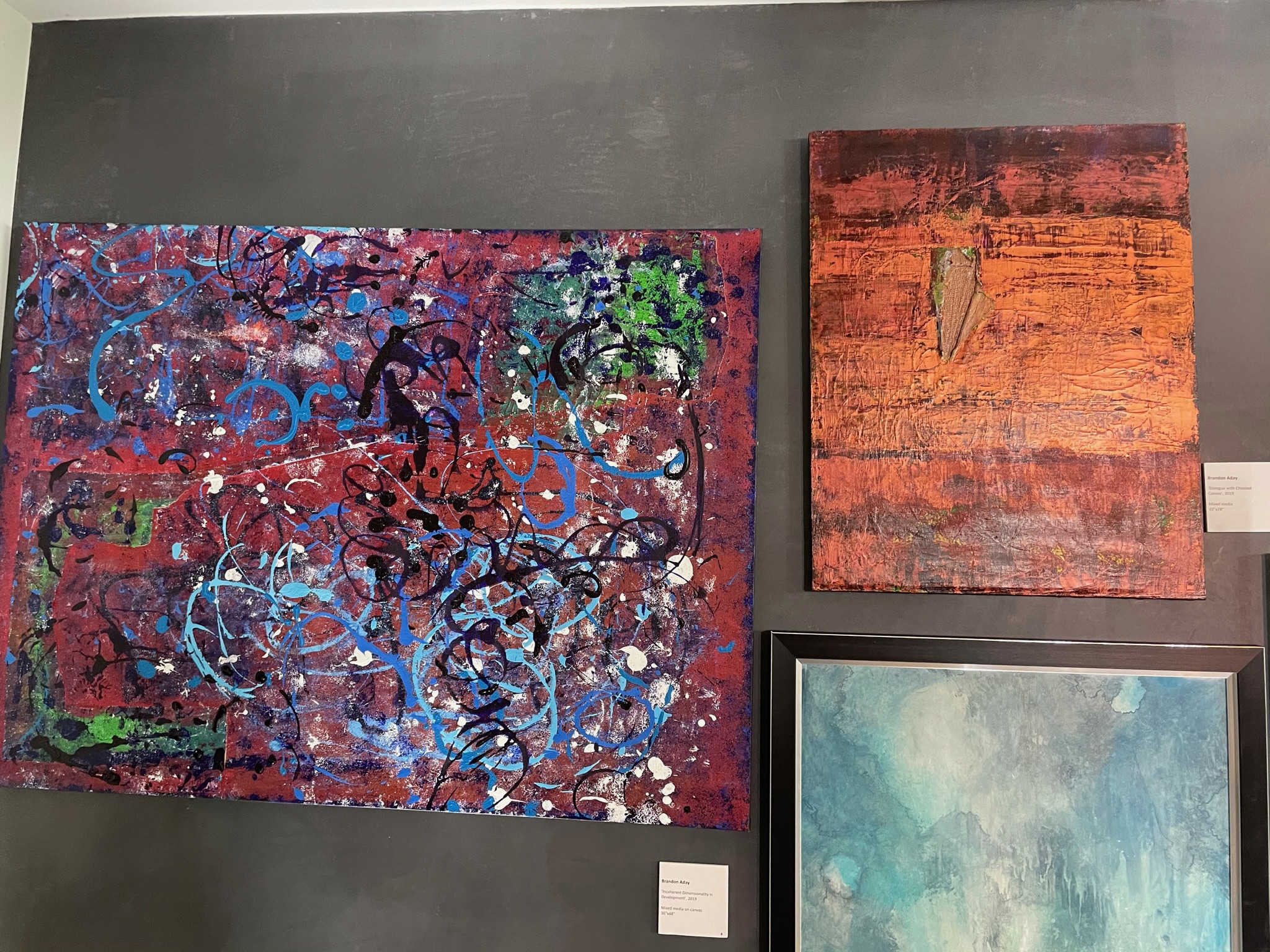 Three works installed on a dark gallery wall.