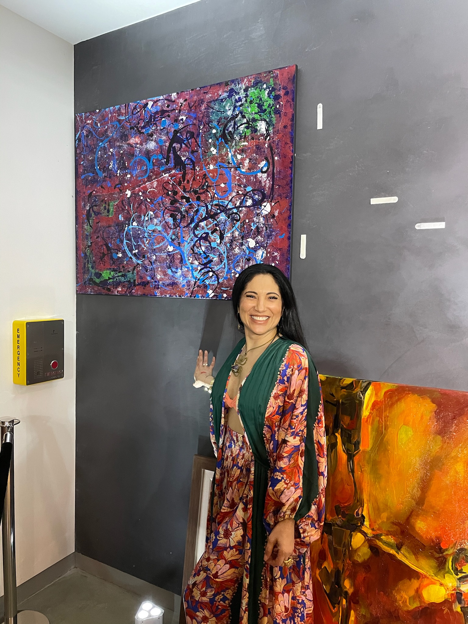 A guest stands beside a newly placed canvas on a gallery wall.