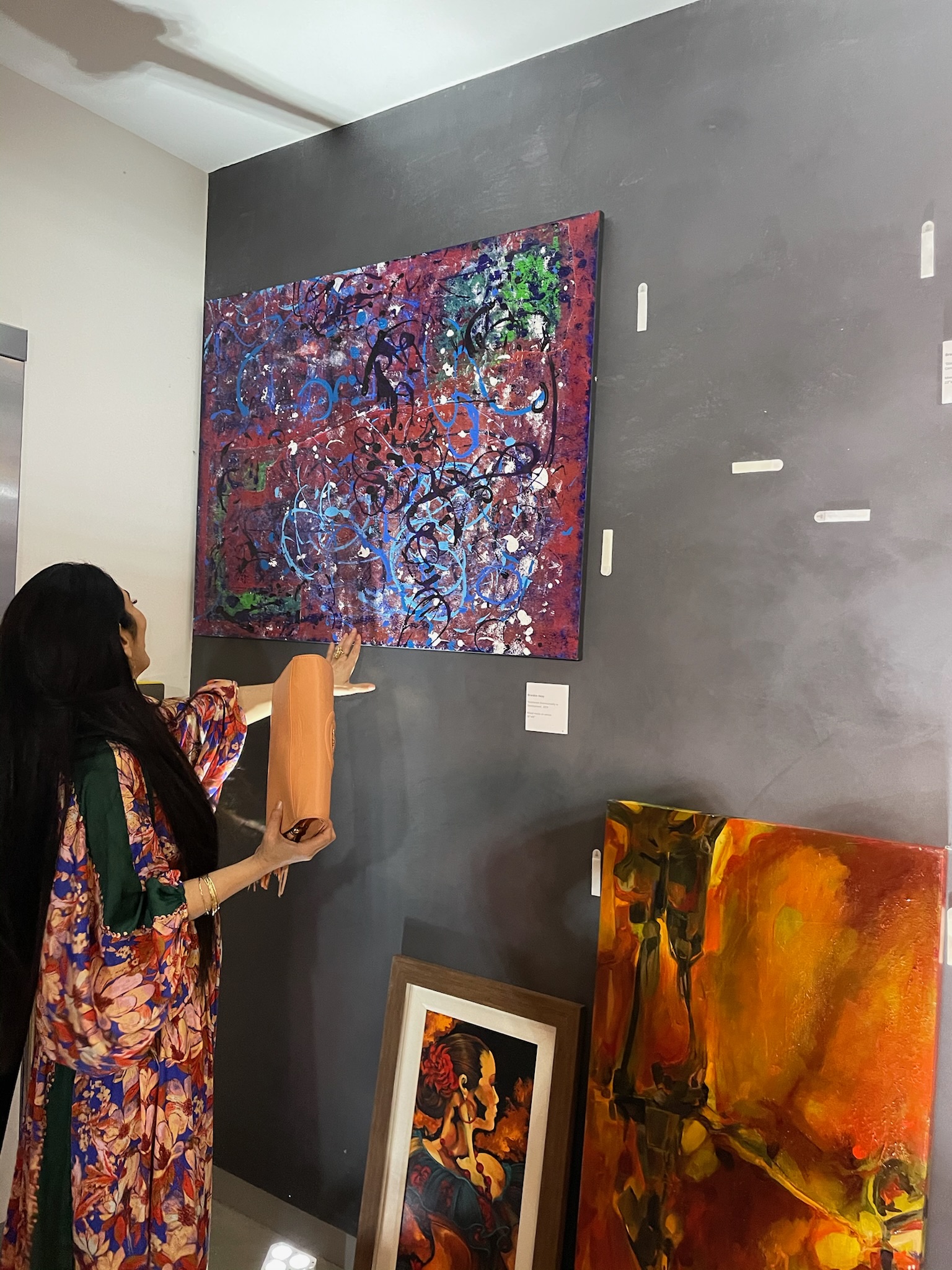 A visitor reaches toward a canvas at close range in a gallery.