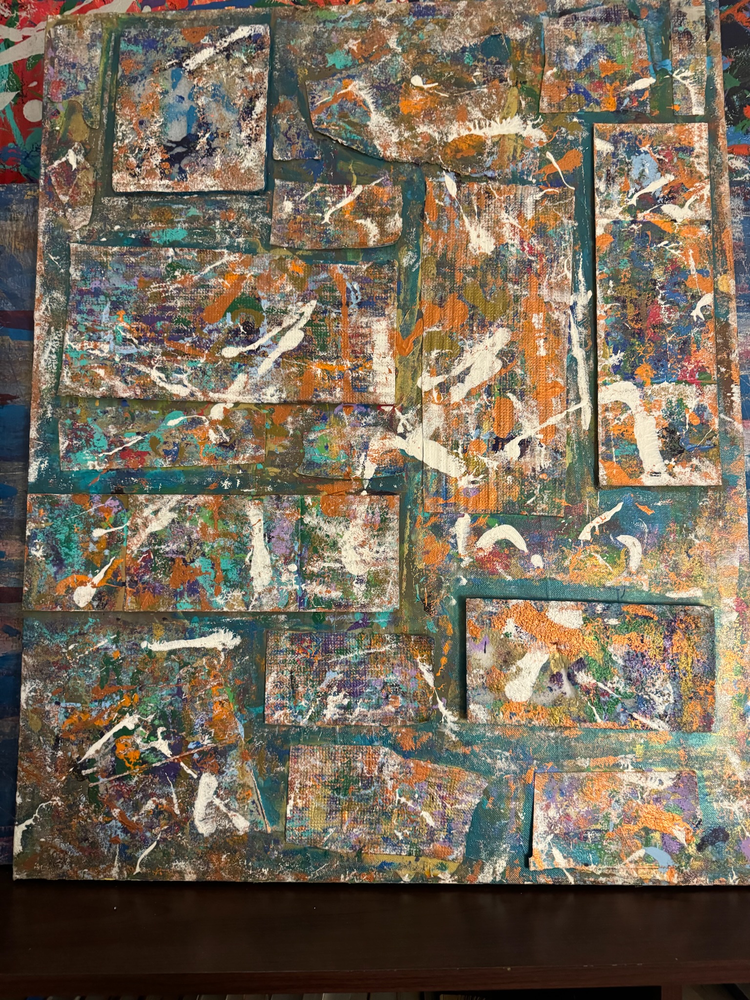 A dense patchwork of textured paint blocks in oranges, teals, and white over a splattered ground.